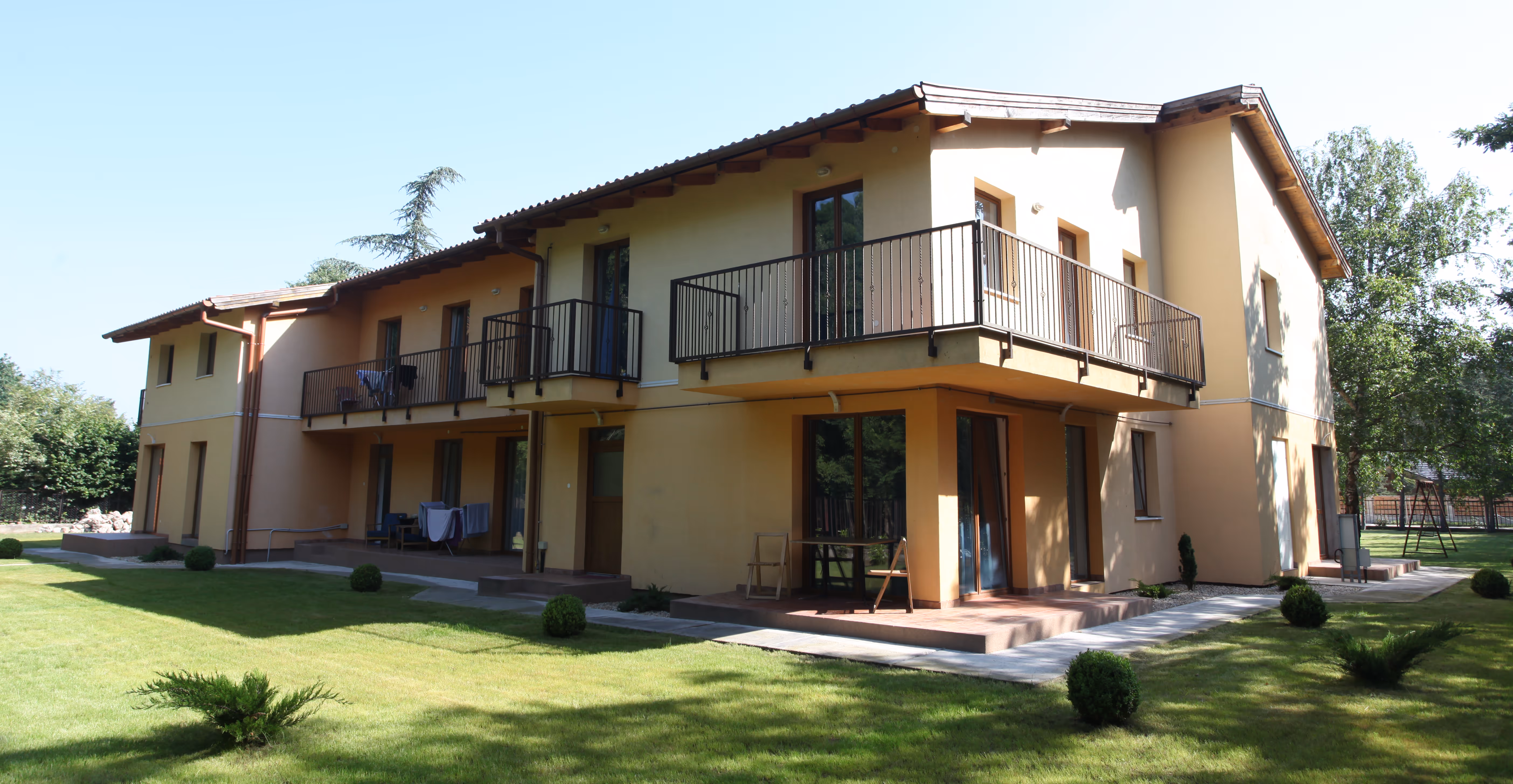 Boglárka utcai munkásszállás – kétszintes mediterrán épület erkélyekkel, zöld gyeppel